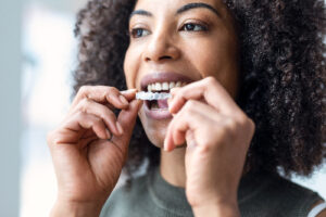 closeup of a young woman placing her Invisalign clear aligners