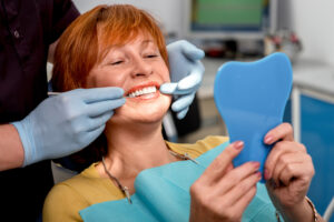 dentist in blue gloves showing a female patient her new, natural veneers