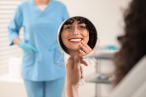 woman looking in a mirror smiling, happy with newly bonded teeth