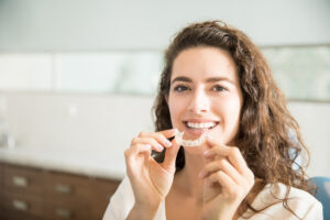young woman placing her clear aligners in her mouth