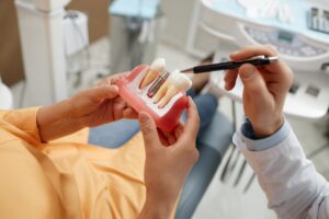 closeup of a female dental patient being shown a implant model by a dentist